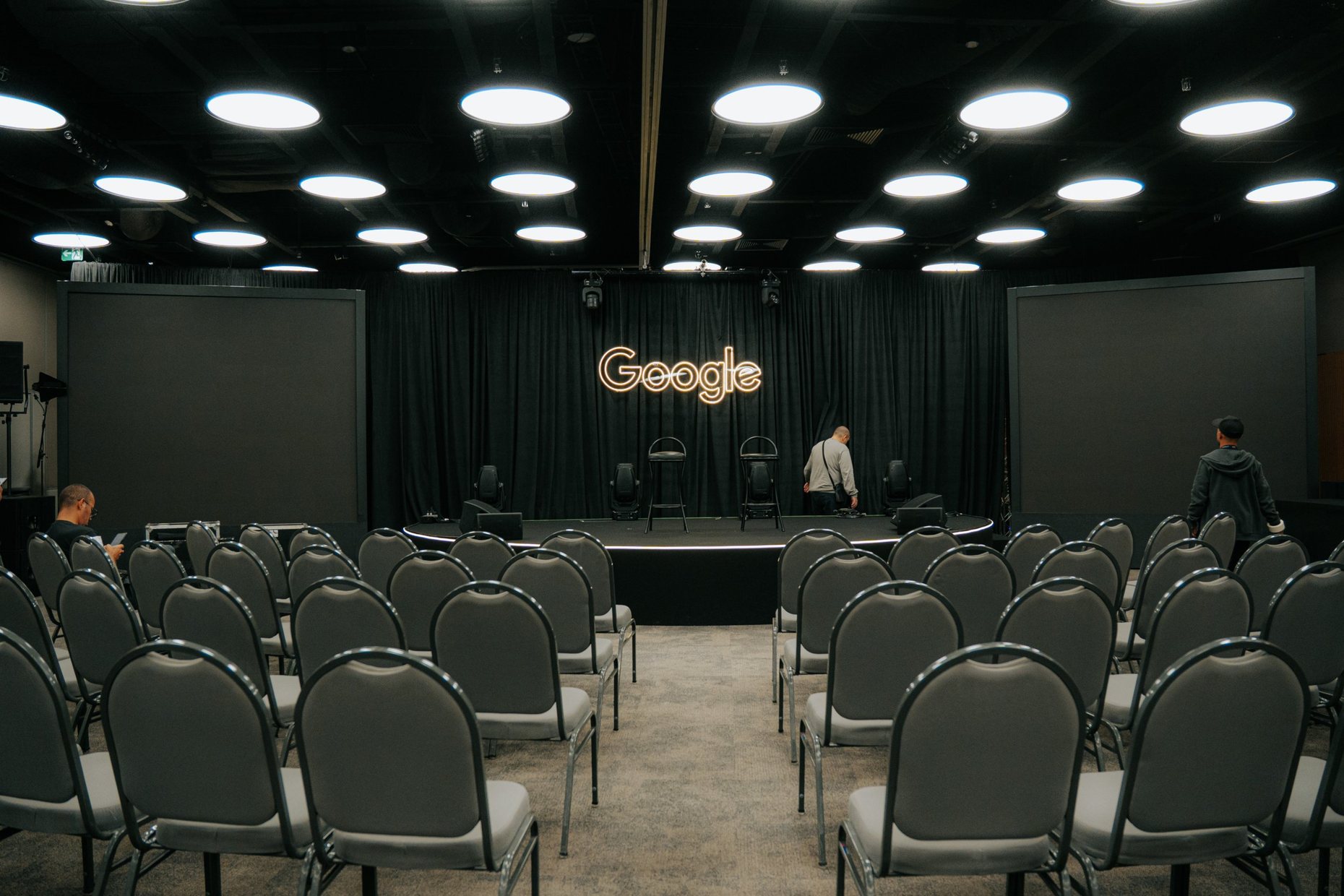 Plateia vazia diante de um palco com o logo do Google em neon